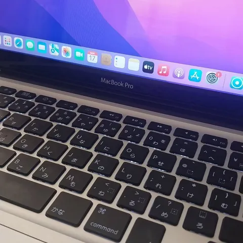 MacBook Pro ligado em atendimento na bancada, com o teclado e a barra de aplicativos visíveis