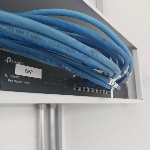 Switch TP-Link de 16 portas identificado como SW1, com cabos de rede azuis organizados